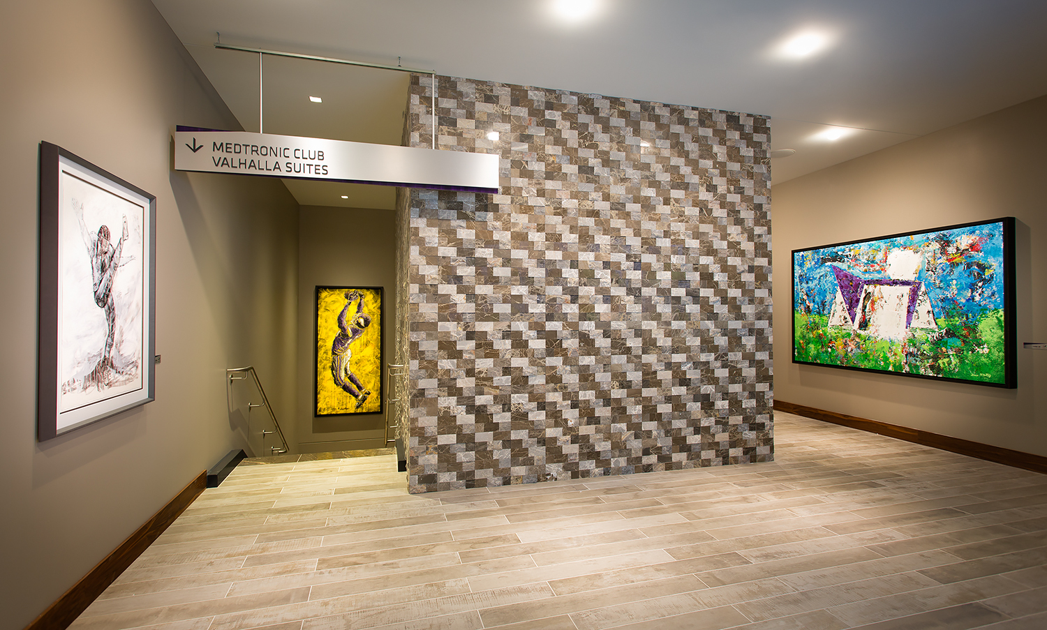 Gallery entrance with artwork on display. A textured stone wall leads into a hallway.