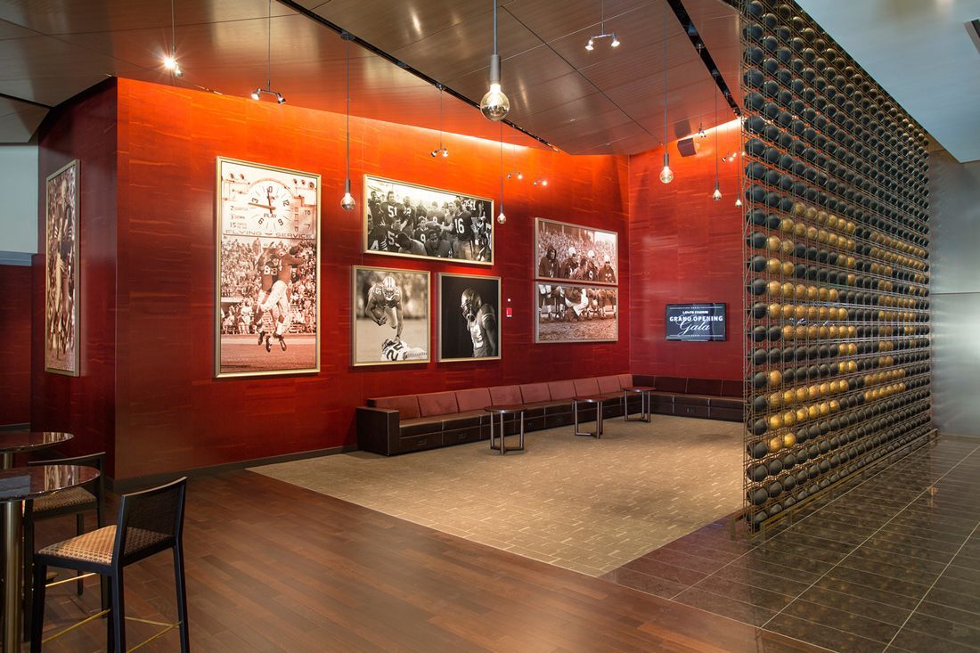 Red-walled gallery with photographs, seating, and a decorative wine rack.