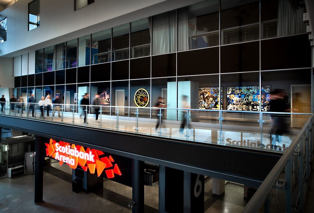 Interior of Scotiabank Arena with people walking on a balcony, display of art, and large sign.
