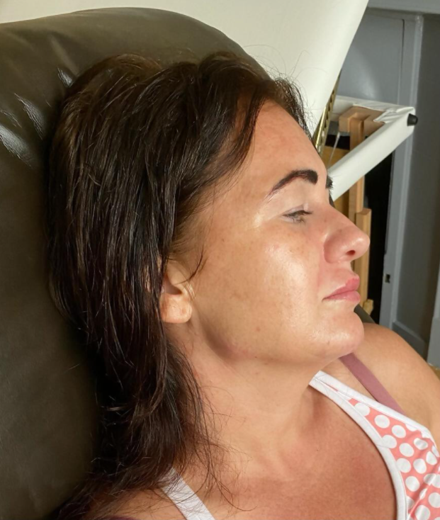 Woman with dark hair, eyes closed, resting. Wearing a polka-dot tank top, in a chair.