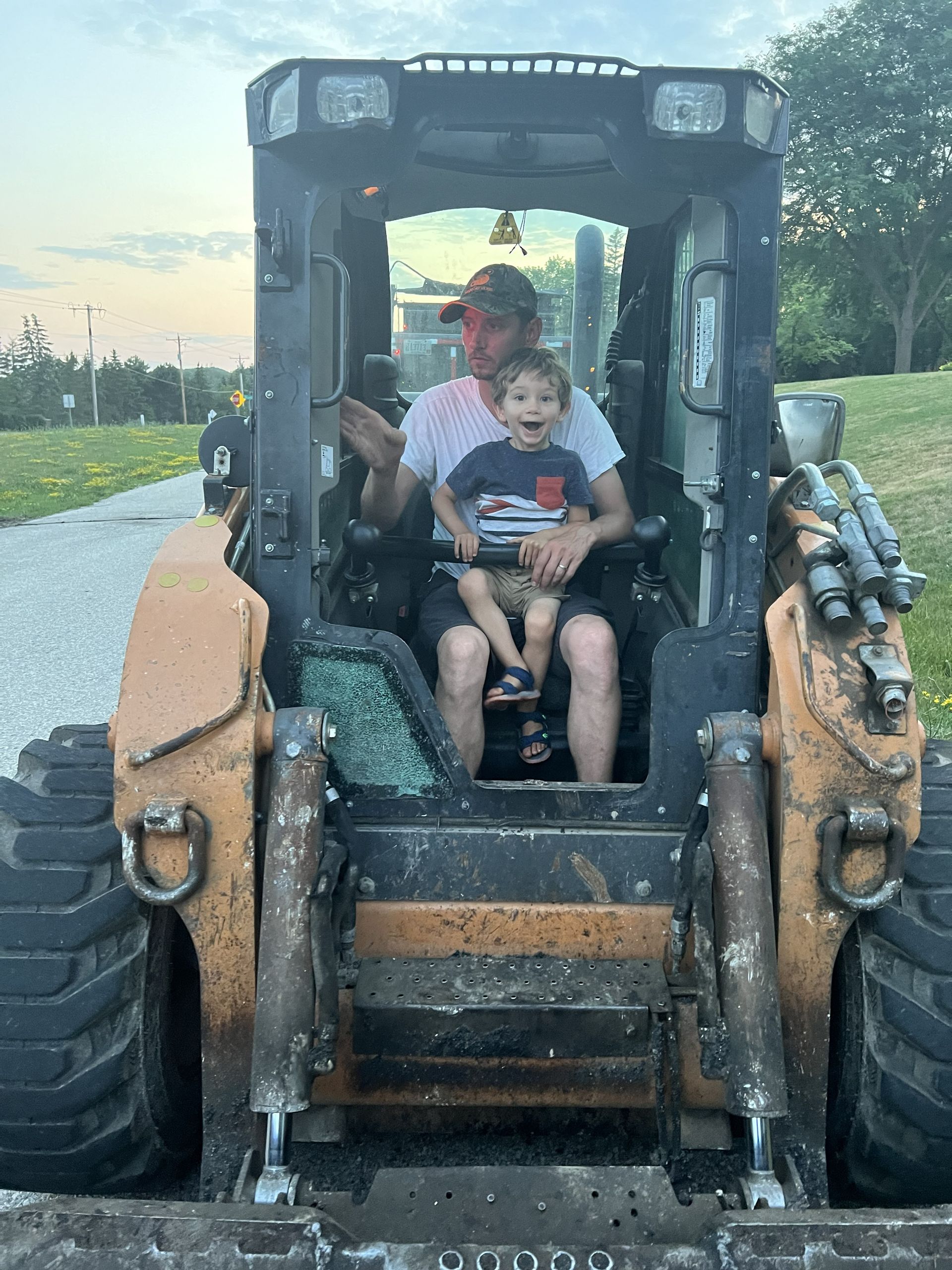 Two children sitting in a rugged off-road vehicle at sunset on a roadside