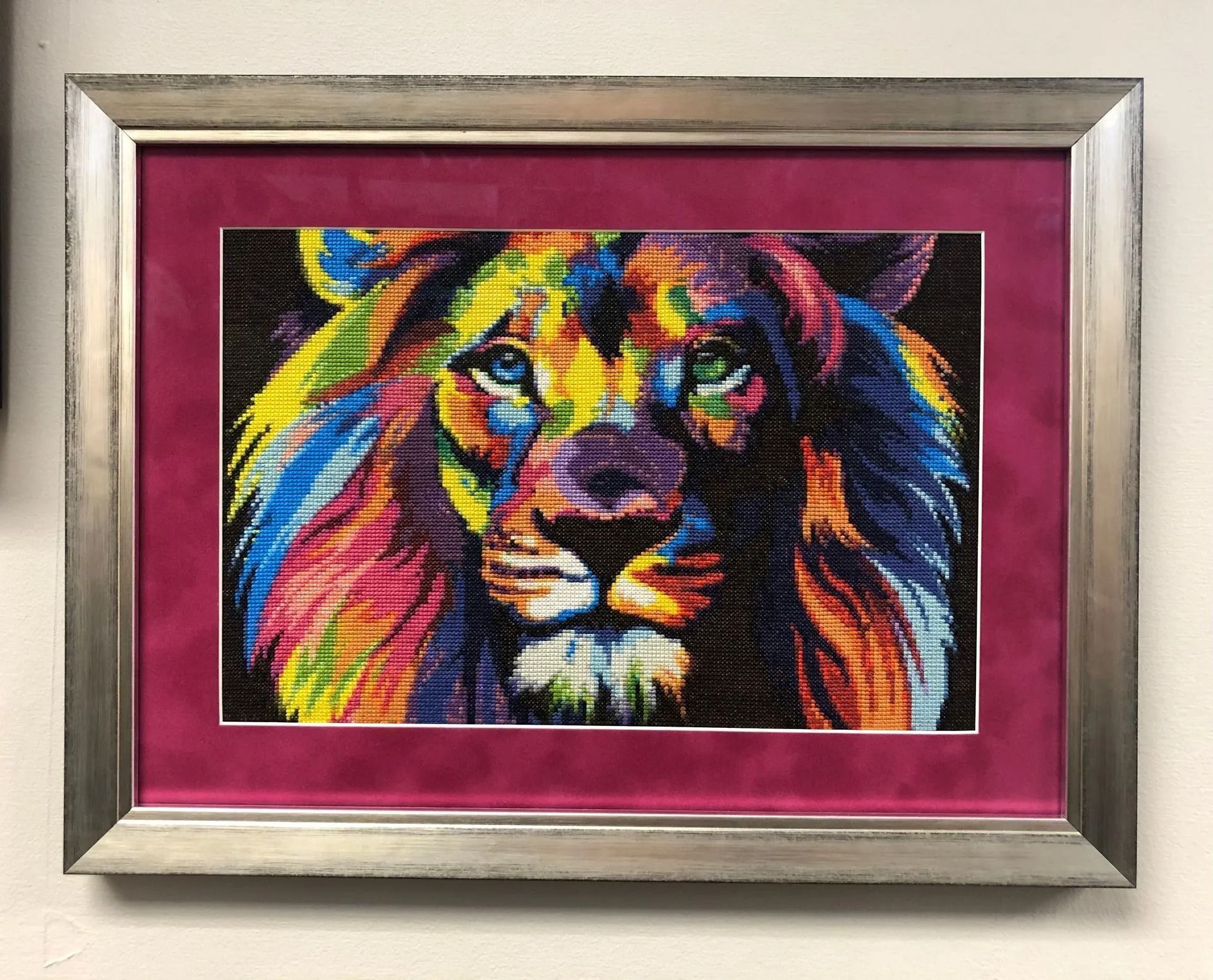 Framed colorful lion portrait with vivid rainbow hues on a magenta mat