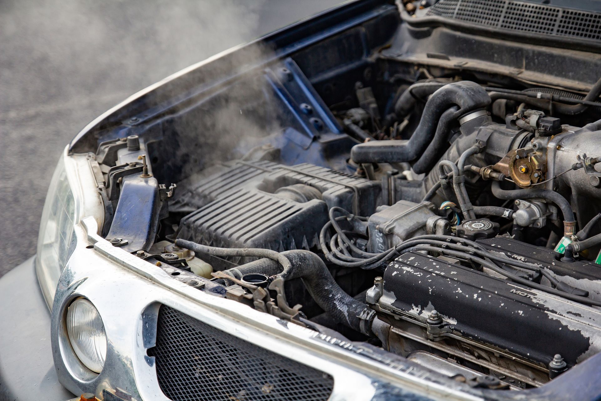 The hood of a car is open and steam is coming out of it.