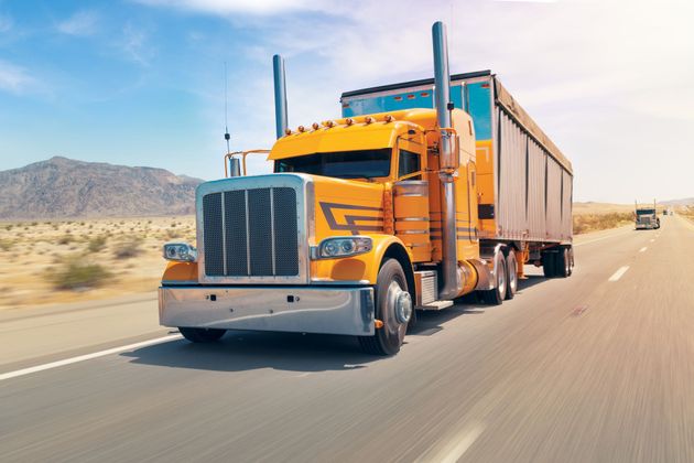 A yellow semi truck is driving down a highway.