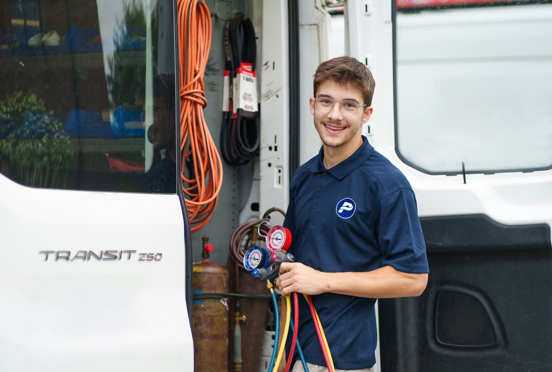 Prevett Heating and Cooling |A young man is standing in front of a white van holding a hose.