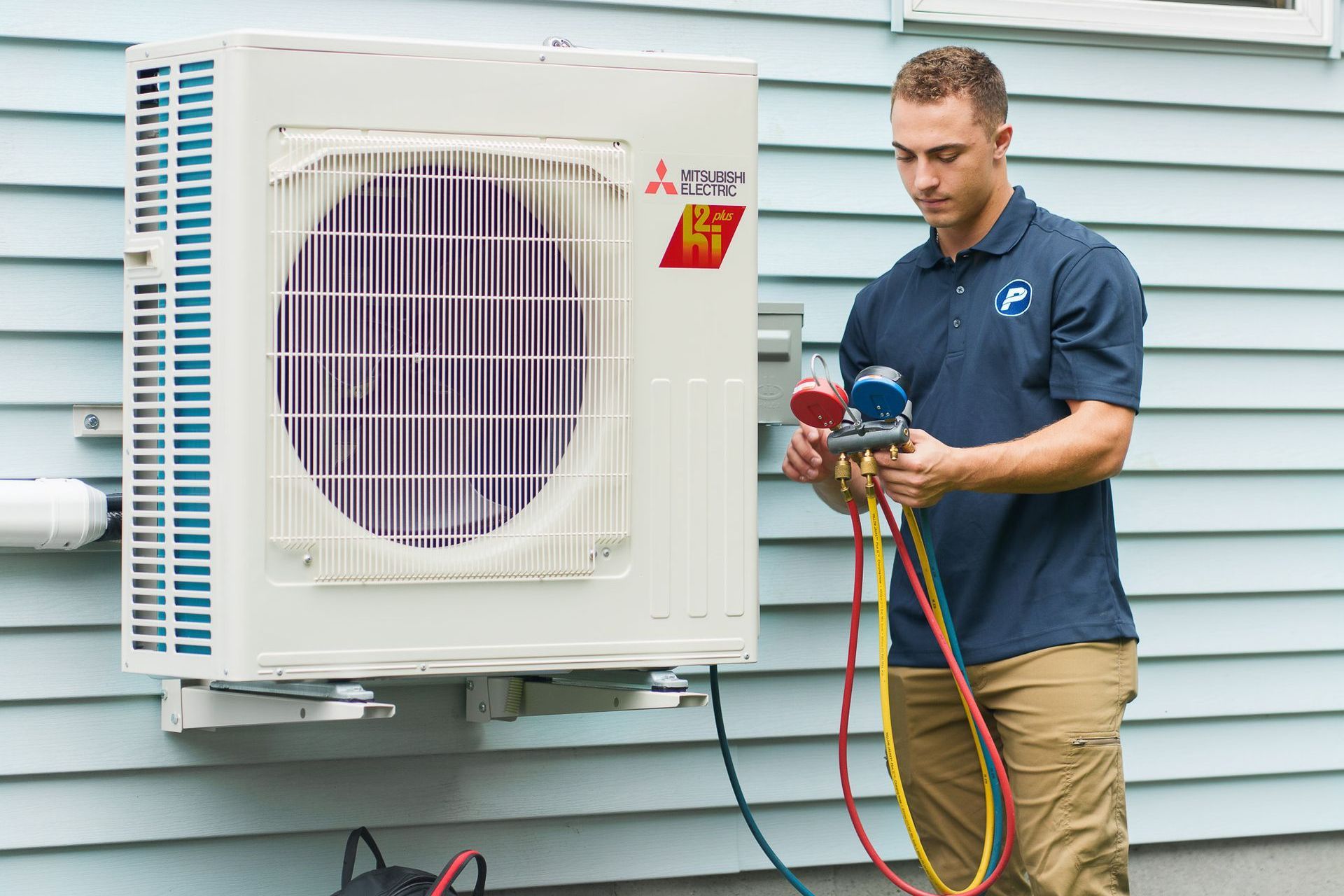 Prevett Heating and Cooling |A man is working on an air conditioner outside of a house.