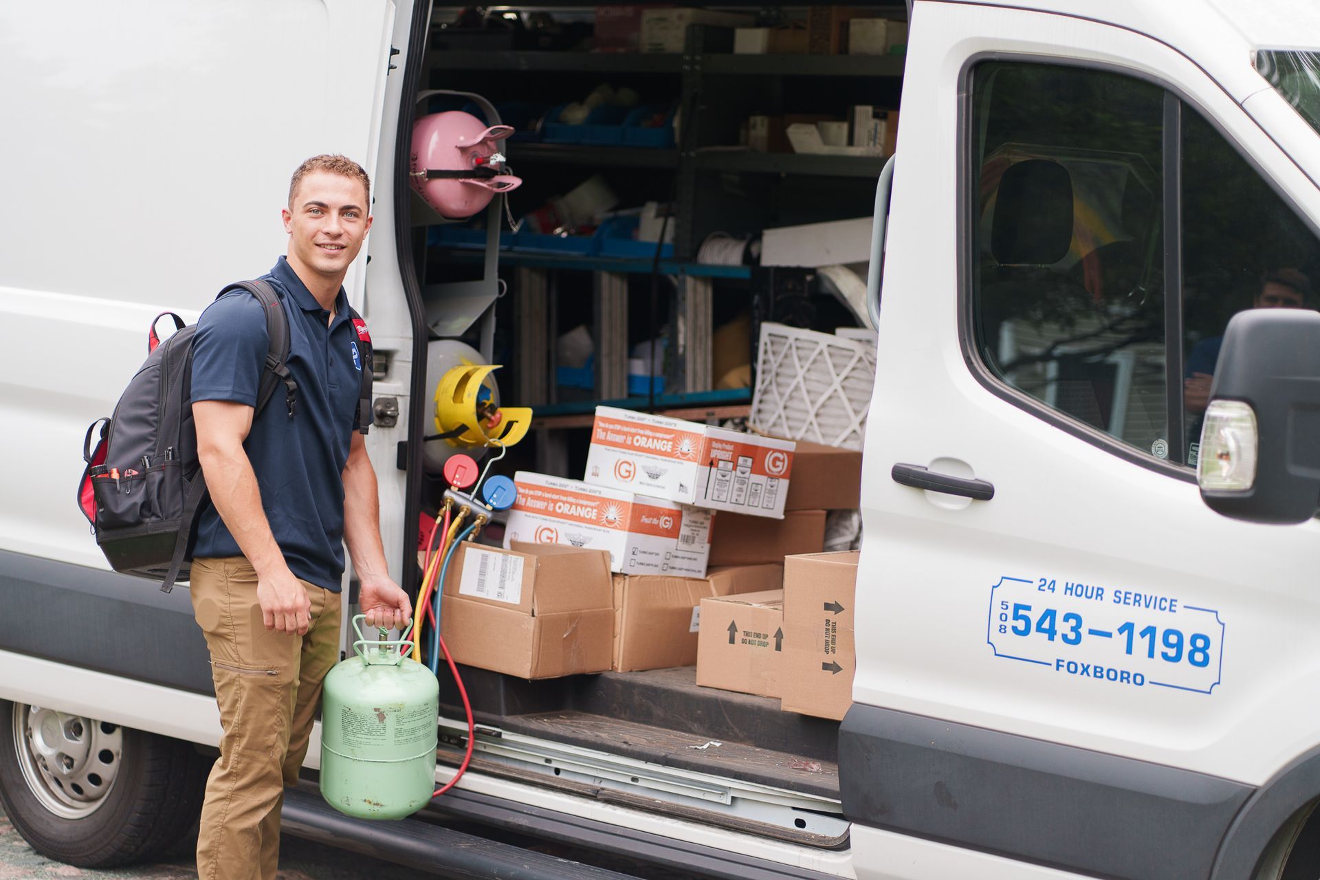 Prevett Heating and Cooling |A man is standing in front of a van holding a propane tank.