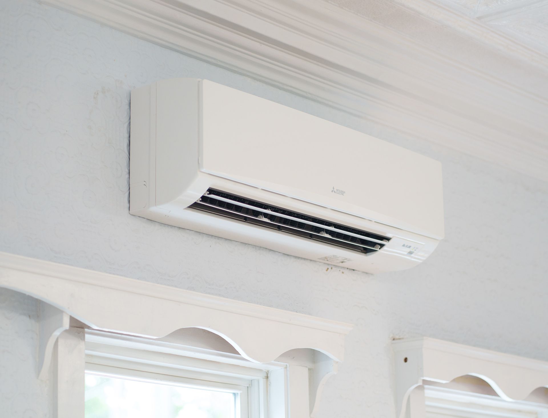 Prevett Heating and Cooling |A white air conditioner is hanging from the ceiling next to a window.