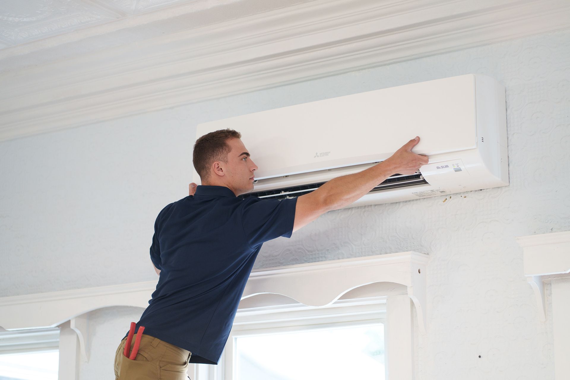 Prevett Heating and Cooling |A man is installing an air conditioner on the wall.