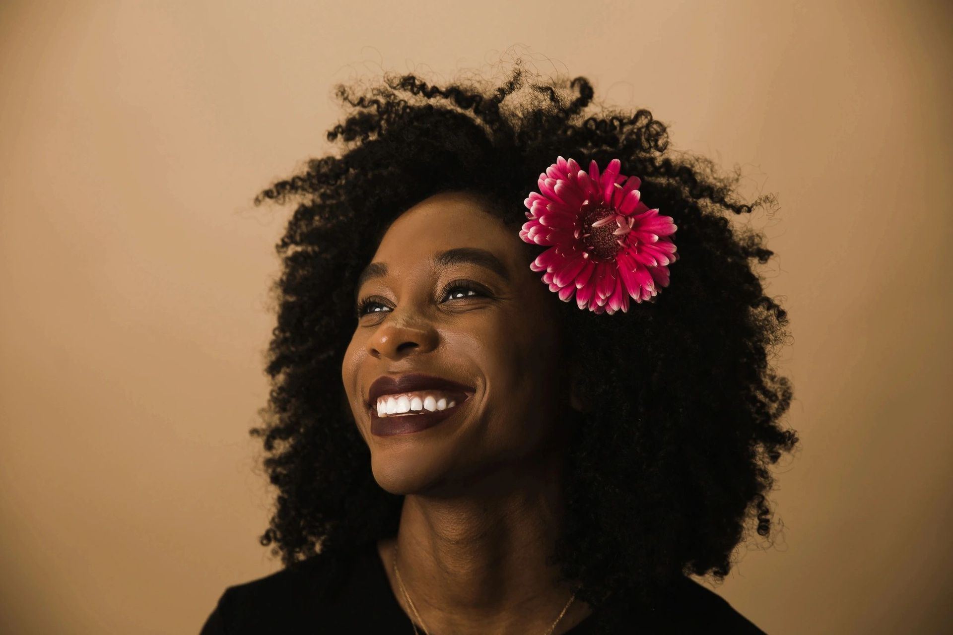 A woman with a flower in her hair is smiling.