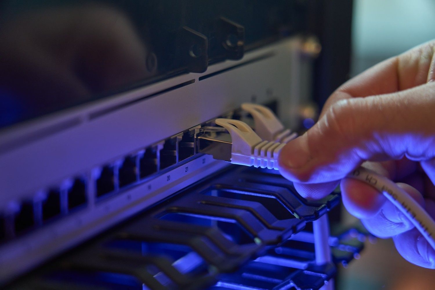 Hand Plugging a White Ethernet Cable Into a Network Switch — Oz Data Tech in Taree, NSW