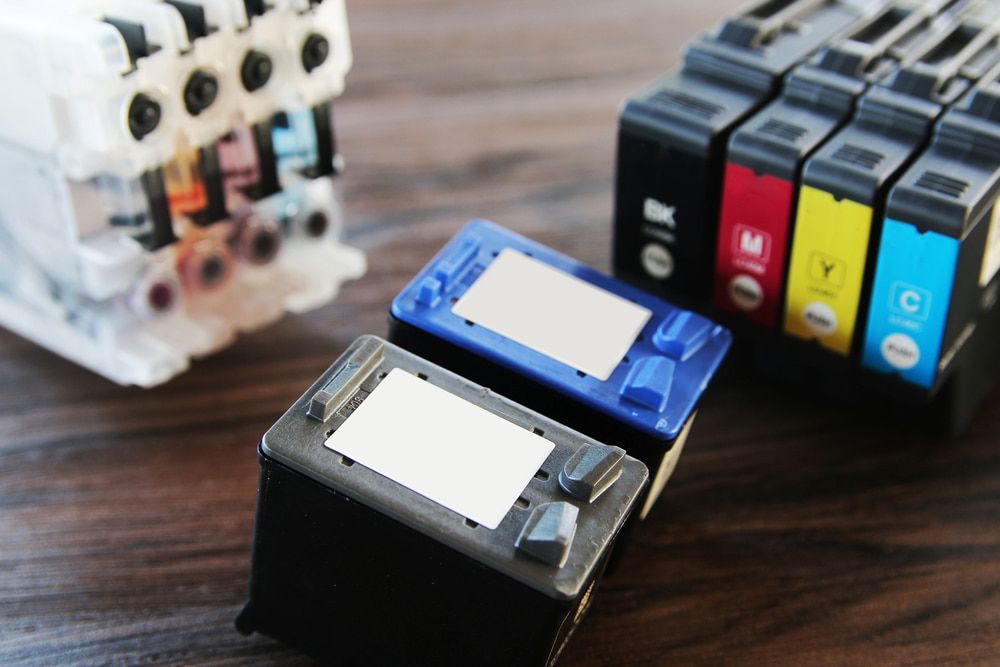 A Bunch Of Ink Cartridges Are Sitting On A Wooden Table — Oz Data Tech in Forster, NSW