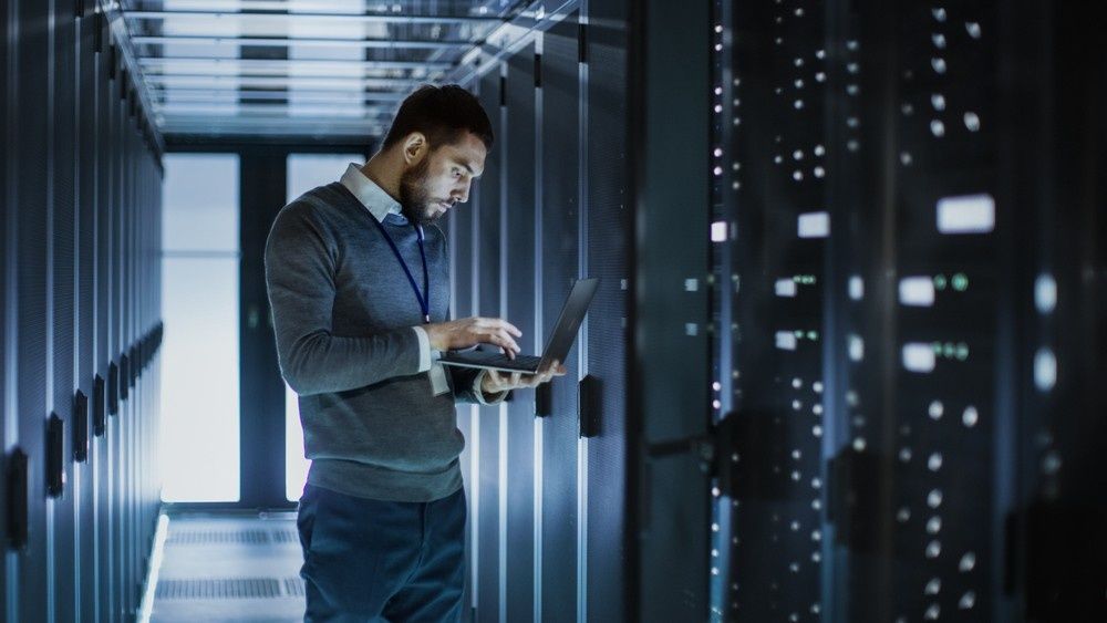 A Man in A Data Center, Using a Laptop to Monitor Server Racks — Oz Data Tech in Taree, NSW