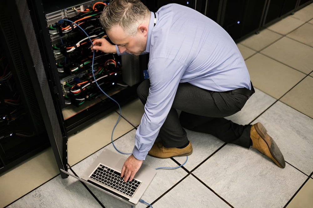 A Man Is Kneeling On The Floor Using A Laptop Computer β Oz Data Tech in Forster, NSW