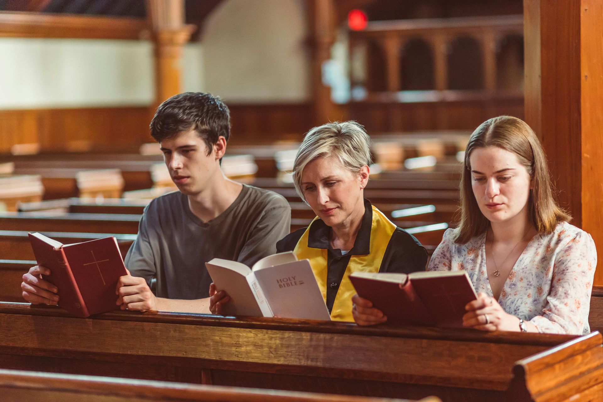 A group of people are sitting in a church reading.