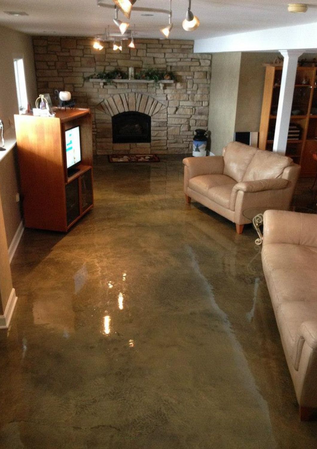 A living room with a couch , chair , television and fireplace.