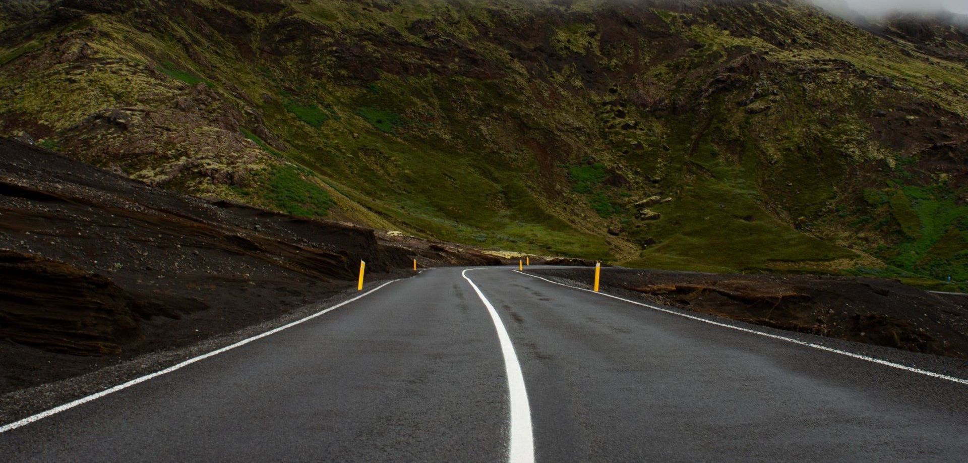 a road going through a mountainous area with a white line on it .