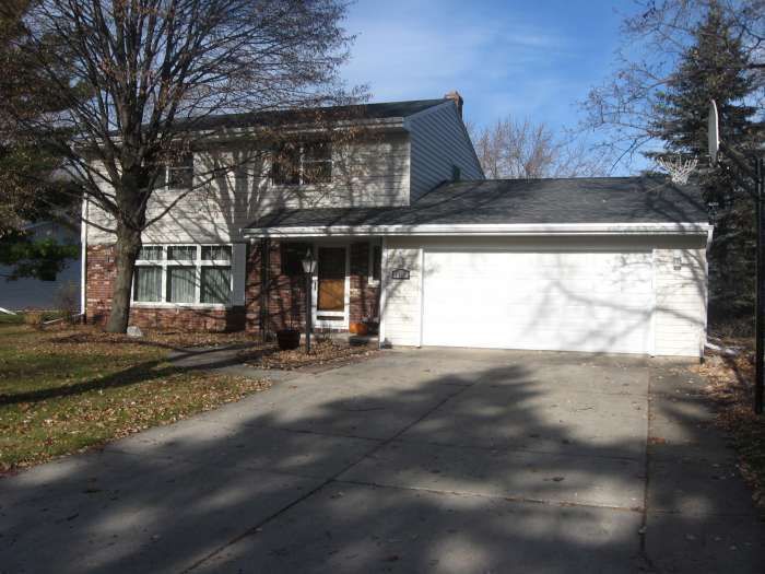 Suburban house with attached white garage and driveway, viewed from the street