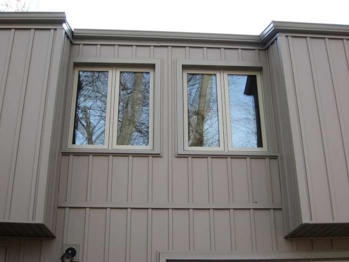 Exterior of a beige house with two windows and vertical siding
