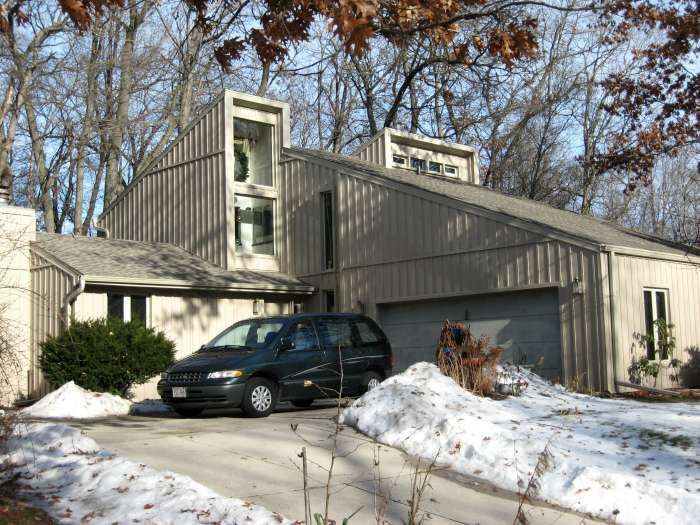 Snowy suburban house with a dark minivan parked in the driveway
