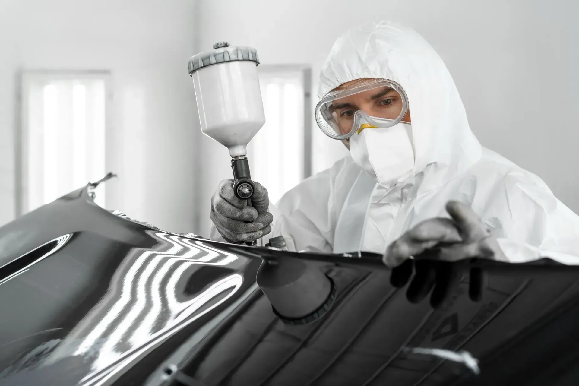 A man in a protective suit is painting a car.