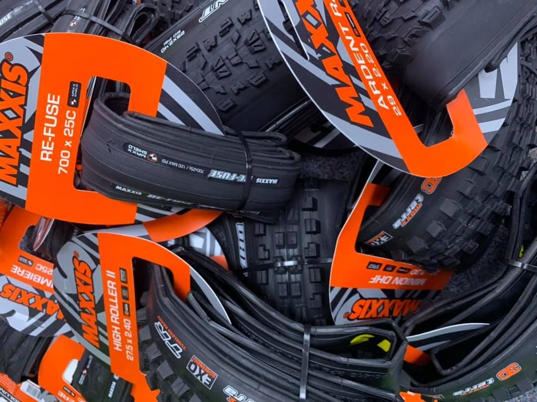 Pile of new black Maxxis bike tires with orange and gray packaging — Grafton City Cycles in Grafton, NSW