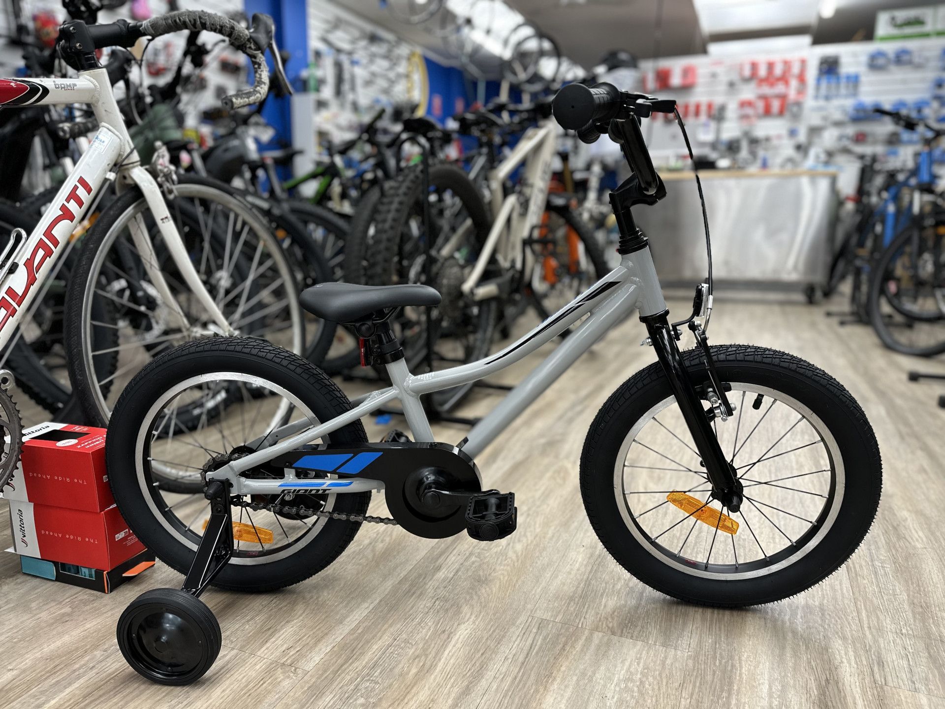 A gray children's bicycle with training wheels sits in a bike shop — Grafton City Cycles in Grafton, NSW