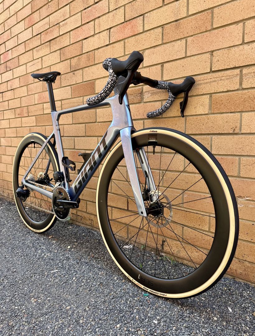 A dark blue road bicycle with white tires leaned against a brick wall — Grafton City Cycles in Grafton, NSW