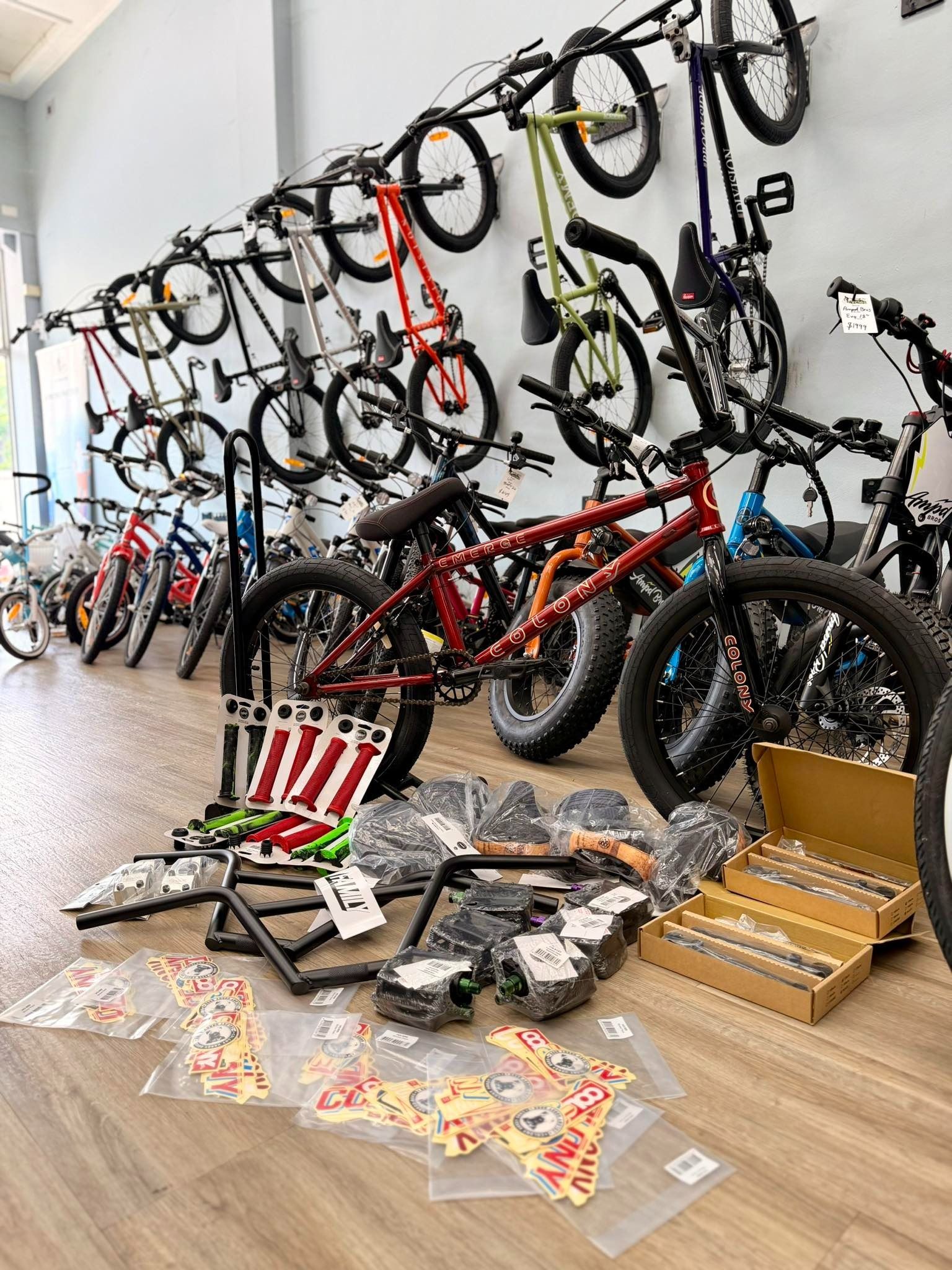 Bikes on display in a shop, with parts laid out in front. Red, green, black and yellow bikes. Wooden floor — Grafton City Cycles in Grafton, NSW
