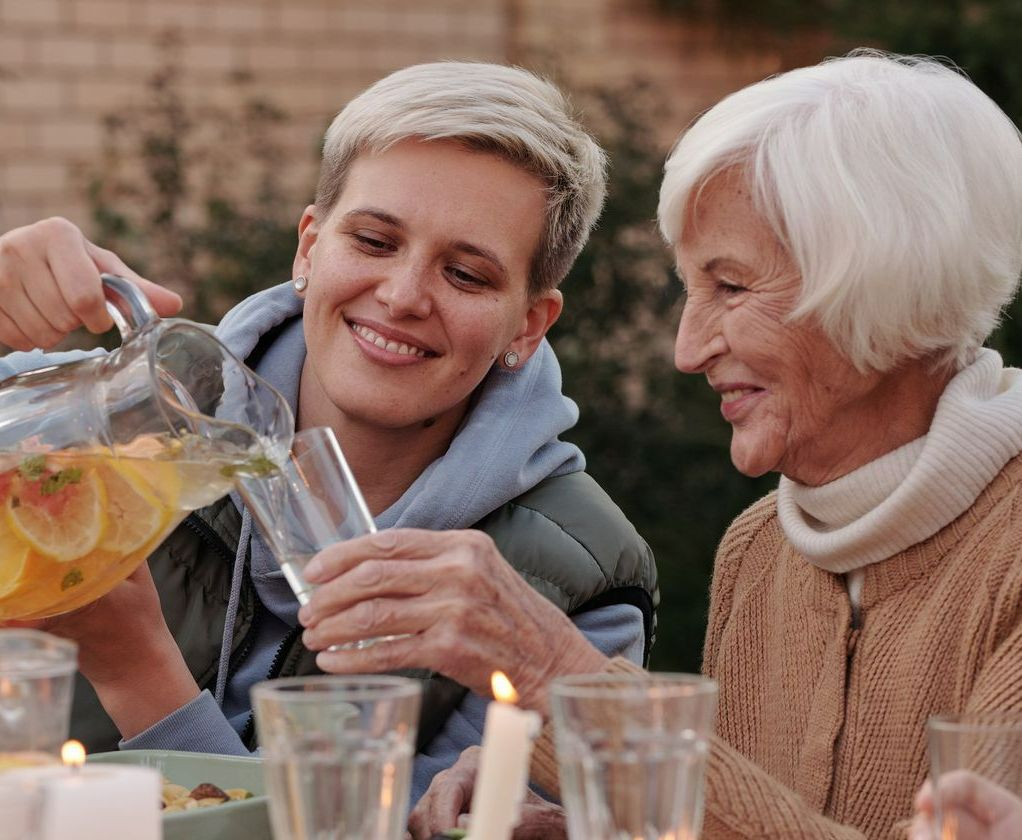 A granddaughter and her grandmother sat outside at a dinner party enjoying a drink