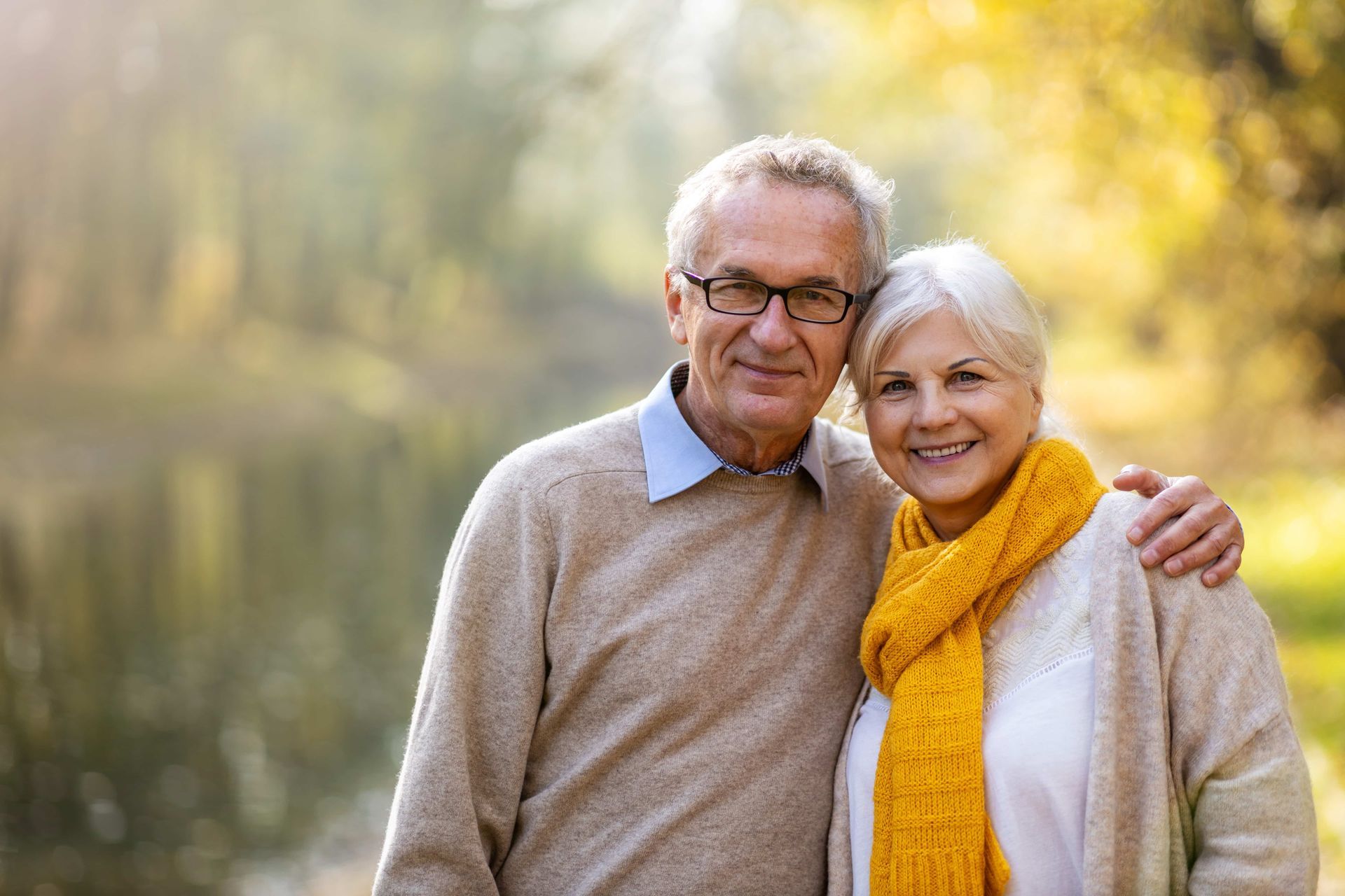An elderly couple standing next to each other in a park.
