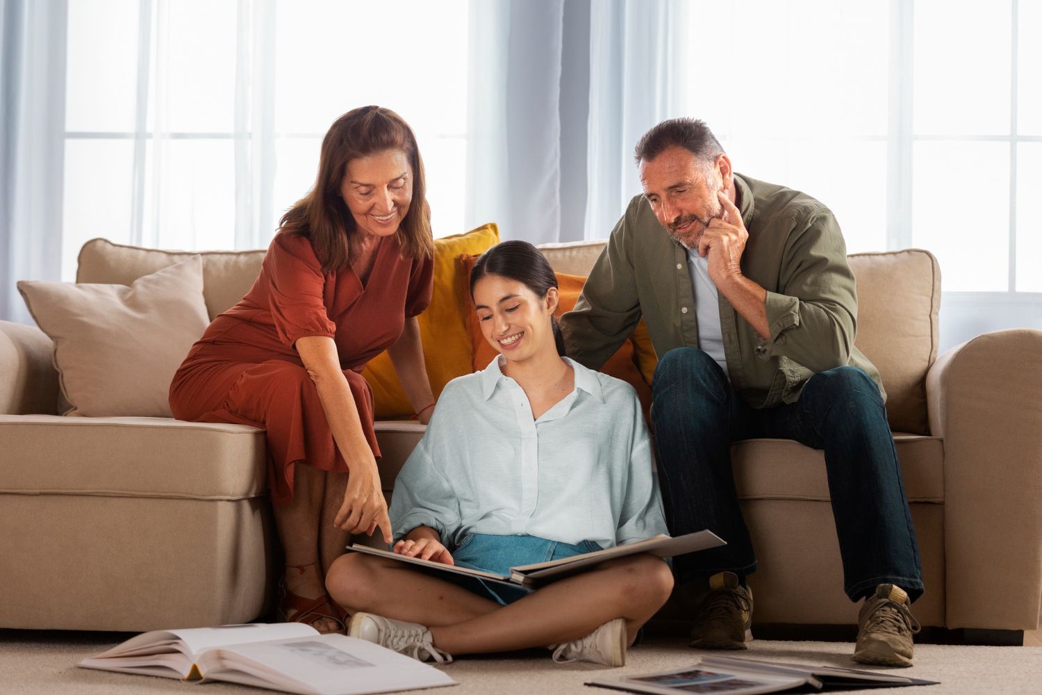 A family is sitting on a couch looking at a photo album.
