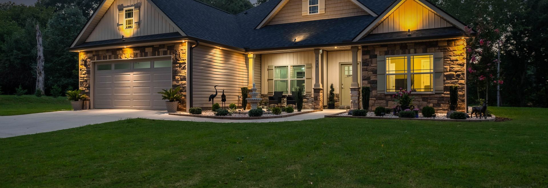 A large house with a garage and a porch is lit up at night.