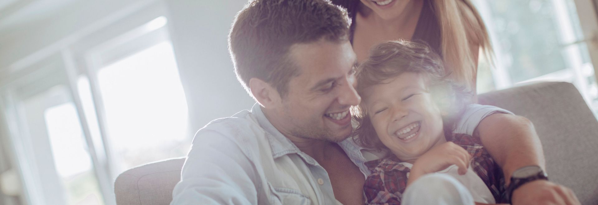 A man and woman are sitting on a couch with a child.