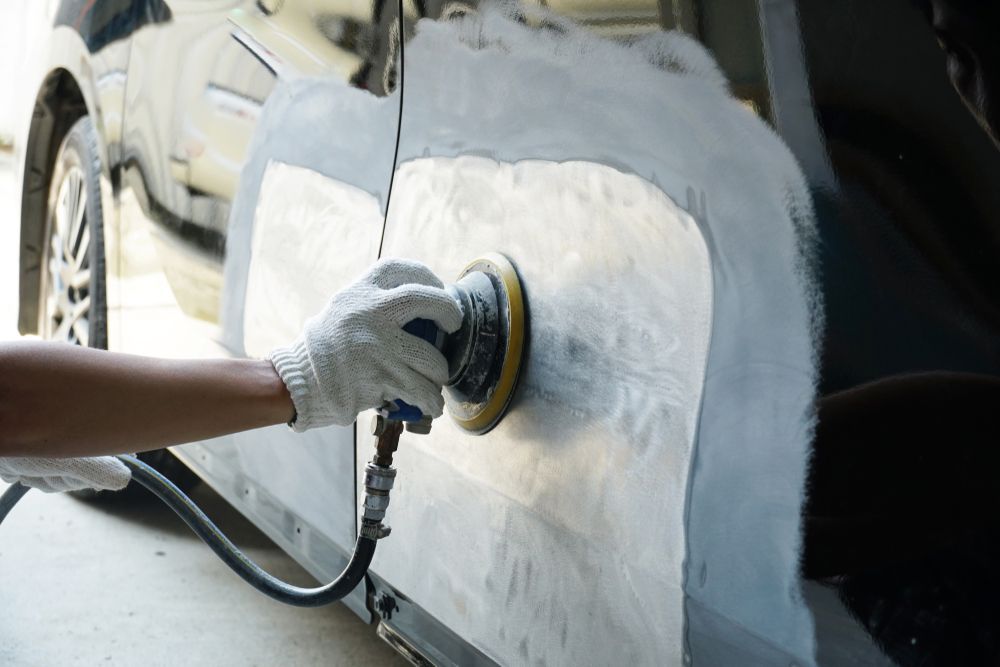 Gloved Hand Using a Power Sander on a Car Body Panel During Auto Repair — FNQ Paintless Dent Repair in Edmonton, QLD