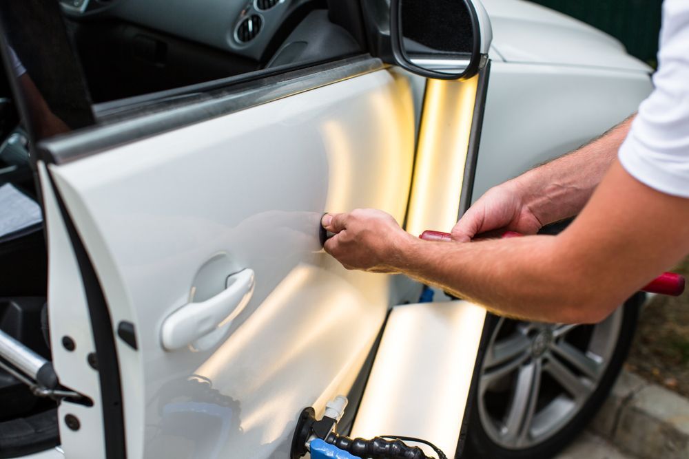 Person Using a Suction Dent Puller on a White Car Door  — FNQ Paintless Dent Repair in Edmonton, QLD