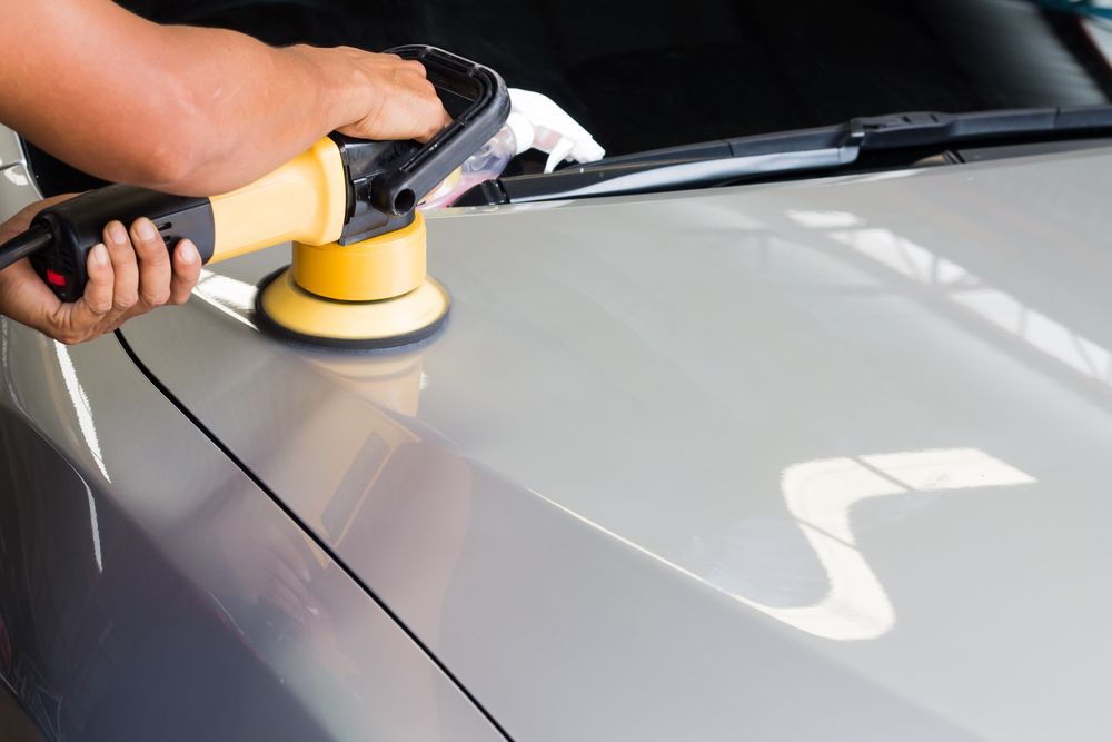 Person Polishing a Gray Car Hood With a Yellow Buffer — FNQ Paintless Dent Repair in Edmonton, QLD