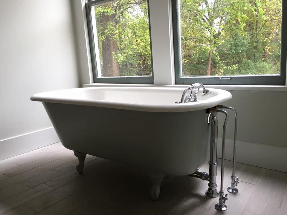 A bathtub is sitting in a bathroom next to a window | emergency plumbing services near me