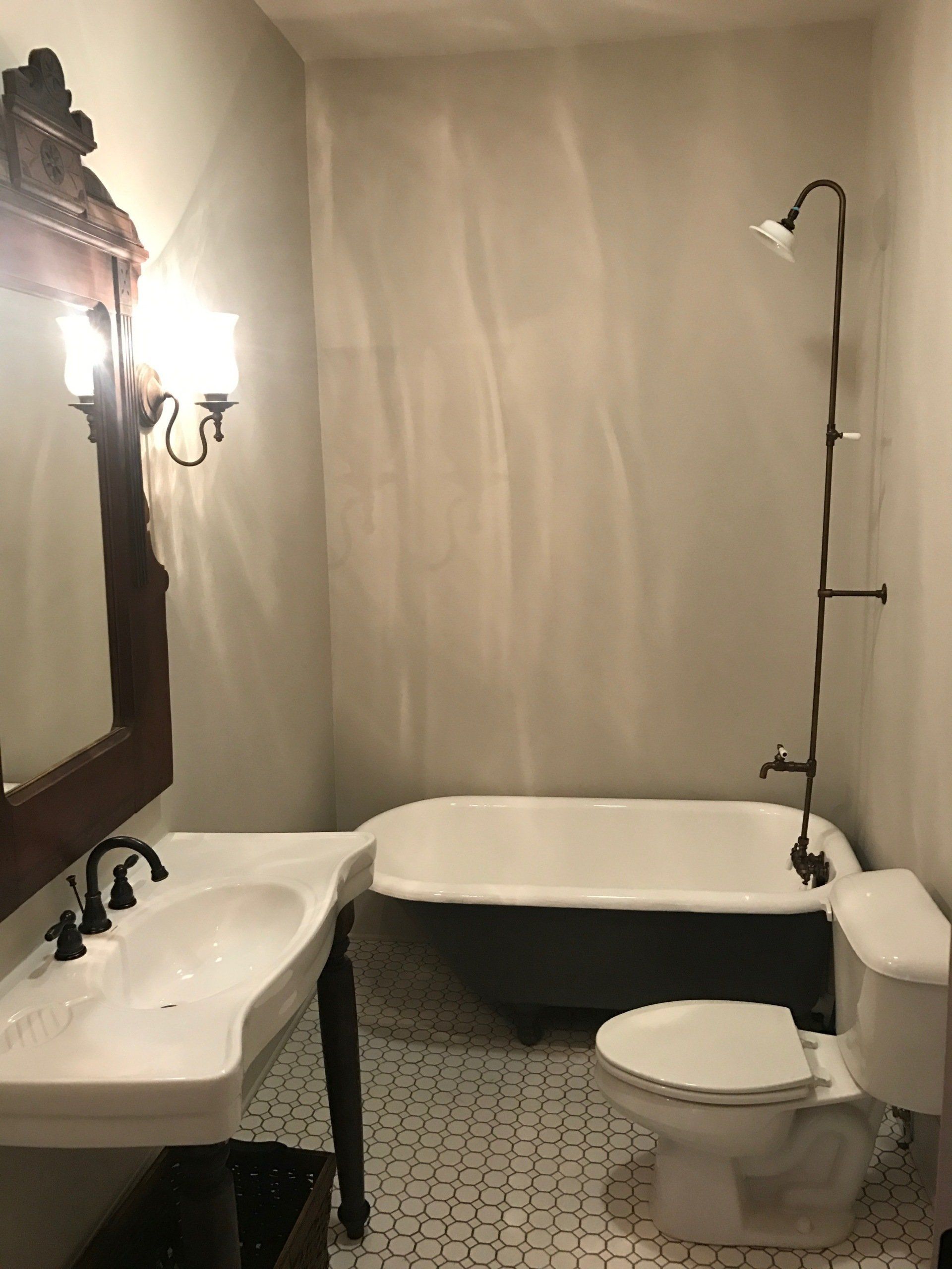 A bathroom with a tub , toilet , sink and mirror | premier construction services