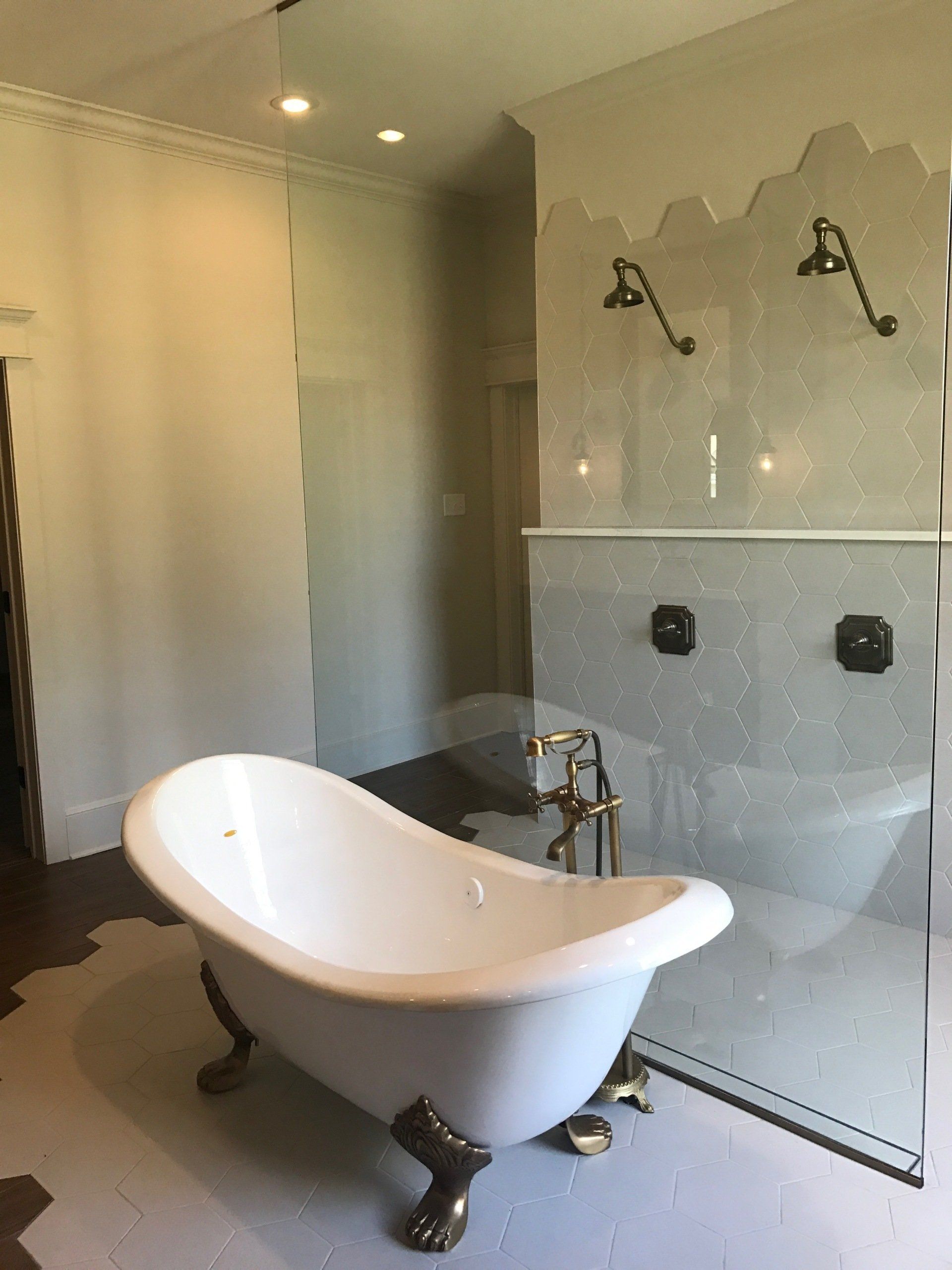A bathroom with a claw foot tub and a walk in shower | residential plumbing repair