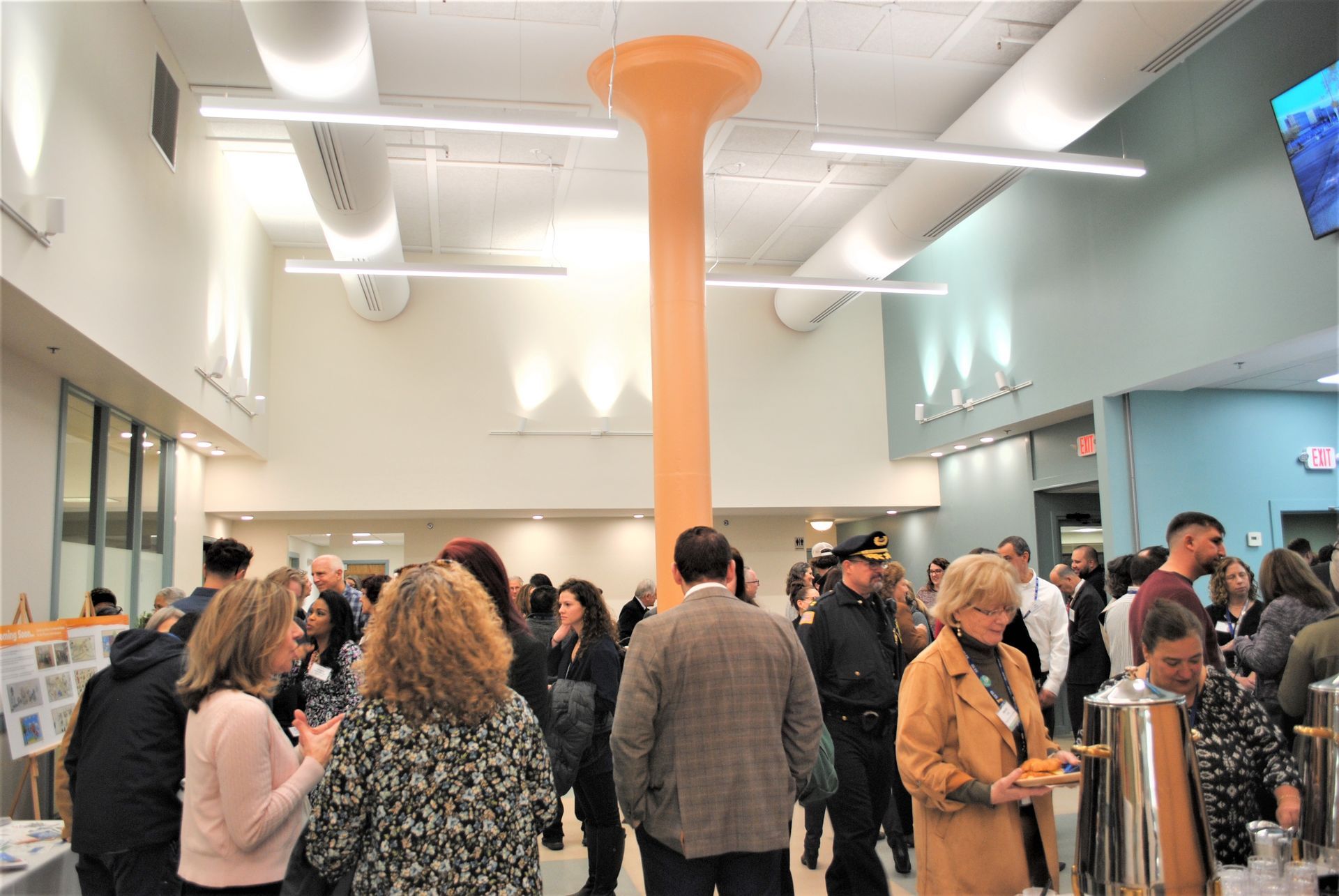 People gather in a modern, bright room with a tall orange column.