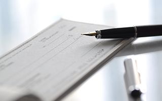 A check with a black pen resting on it.
