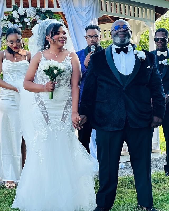 A bride and groom are holding hands in front of their wedding party.