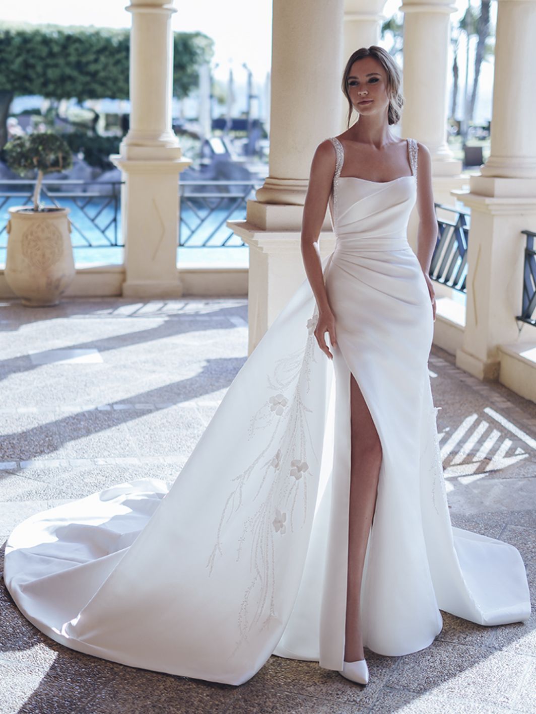 A woman is wearing a white wedding dress with a high slit.