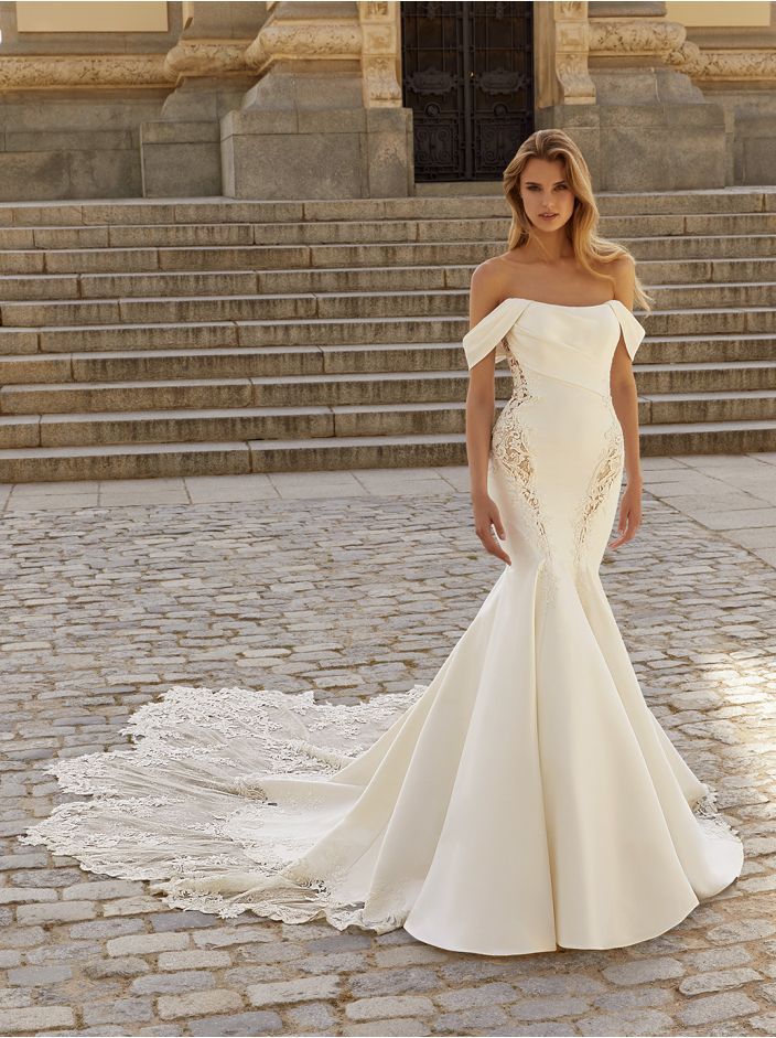 A woman in a white wedding dress is standing on a cobblestone street.