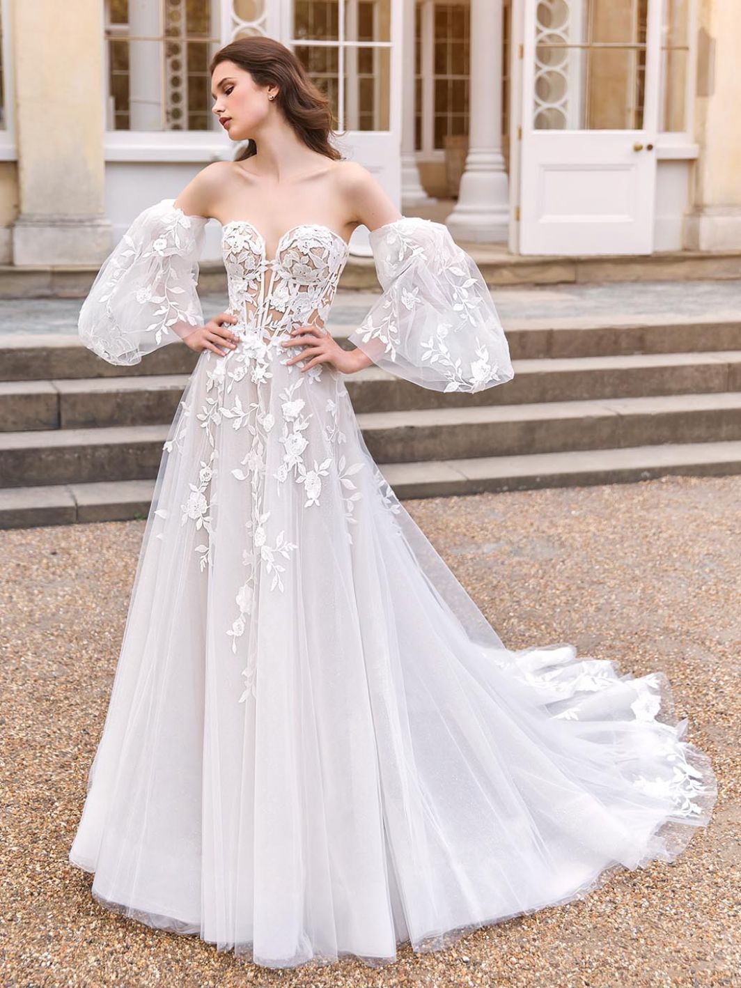 A woman is wearing a white wedding dress with puffed sleeves.