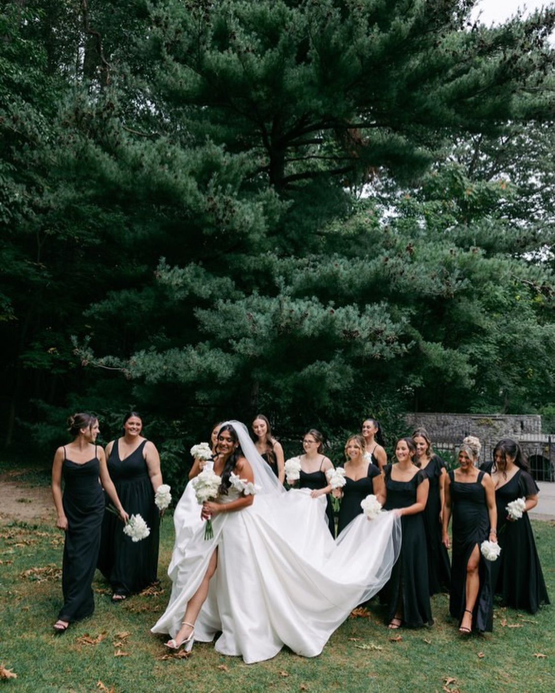 A bride and her bridesmaids are posing for a picture in front of a tree.