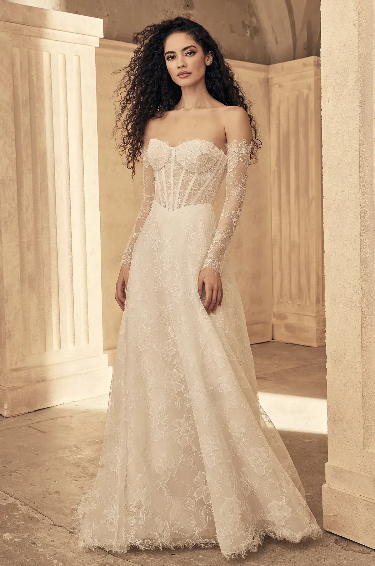 A woman is wearing a white wedding dress with long sleeves.