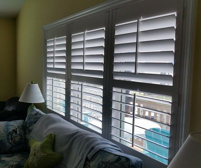 A living room with a couch and shutters on the windows