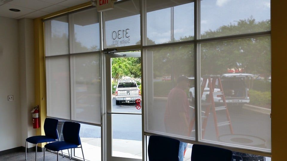 A waiting room with chairs and blinds on the windows.